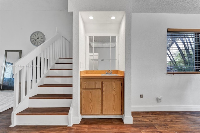 staircase featuring a textured ceiling, baseboards, wood finished floors, and a textured wall