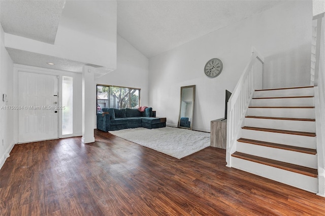 entrance foyer with baseboards, dark wood finished floors, stairway, a textured ceiling, and high vaulted ceiling