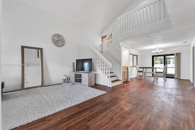 unfurnished living room with dark wood-style flooring, high vaulted ceiling, a textured ceiling, a chandelier, and stairs