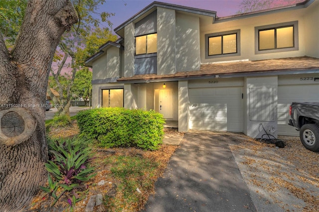 view of front facade featuring a garage, driveway, and stucco siding