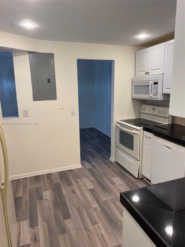 kitchen featuring white appliances, white cabinets, electric panel, dark countertops, and dark wood finished floors