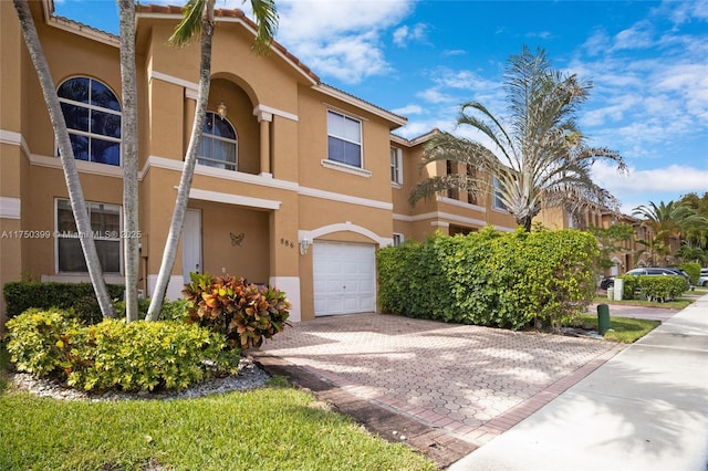 townhome / multi-family property with an attached garage and stucco siding