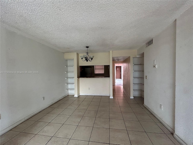 unfurnished living room featuring light tile patterned floors, baseboards, visible vents, a textured ceiling, and a chandelier