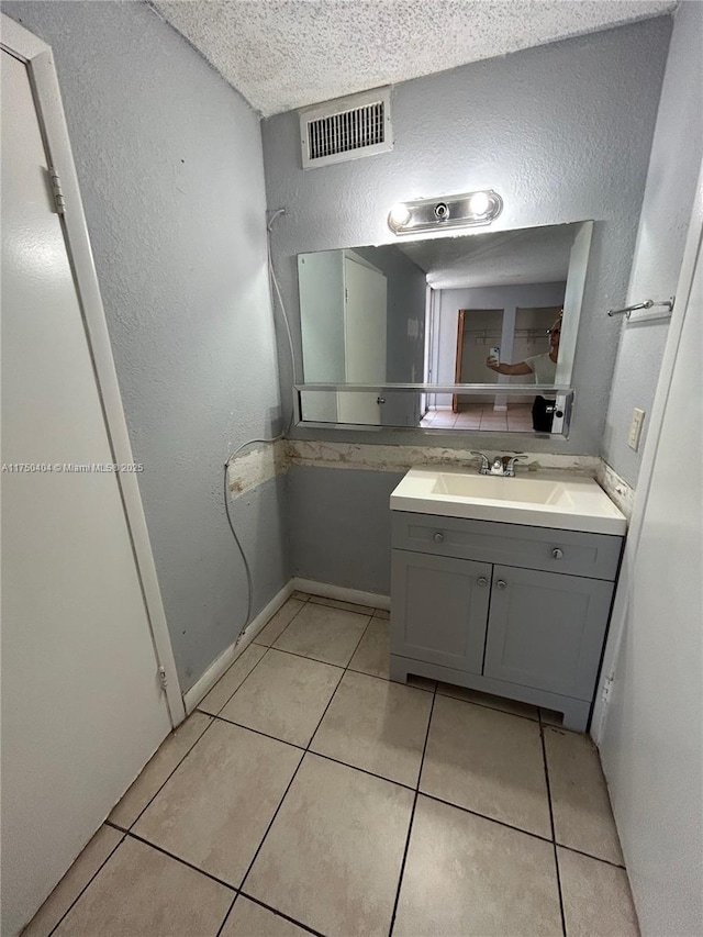 bathroom featuring visible vents, a textured wall, tile patterned flooring, a textured ceiling, and vanity