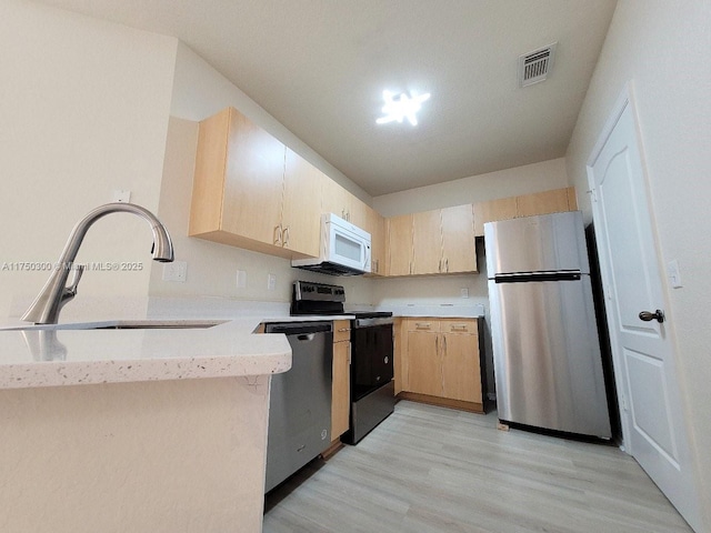 kitchen featuring visible vents, light wood-style flooring, light brown cabinetry, appliances with stainless steel finishes, and a sink