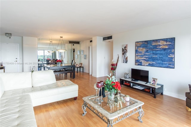 living area with visible vents, baseboards, and wood finished floors