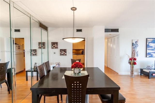 dining area featuring wood finished floors, visible vents, and baseboards