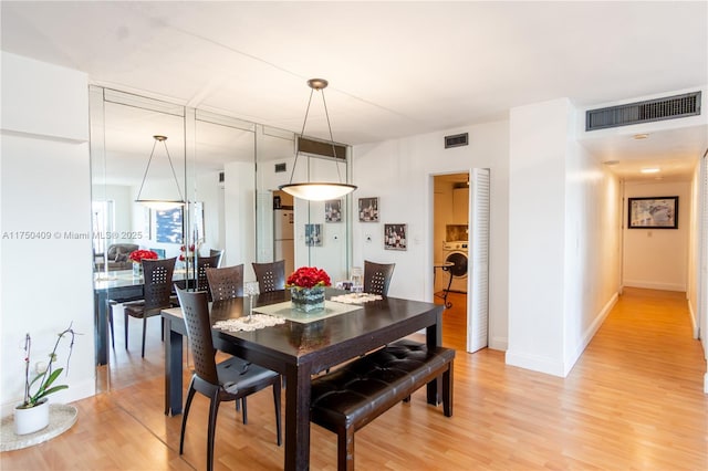 dining room featuring washer / dryer, visible vents, baseboards, and wood finished floors