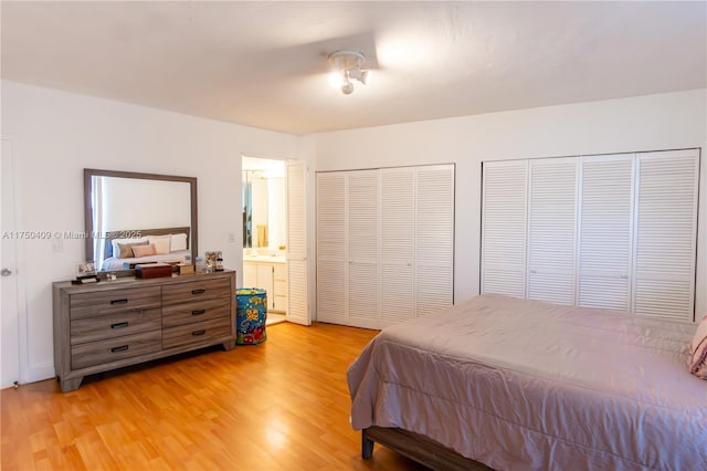 bedroom featuring ensuite bathroom, light wood finished floors, and two closets