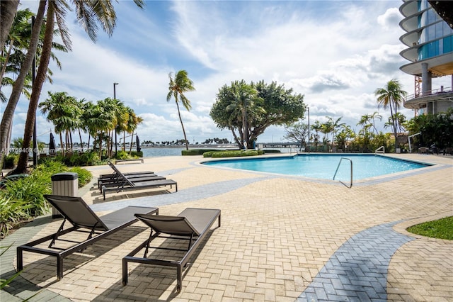 community pool with a patio area and a water view