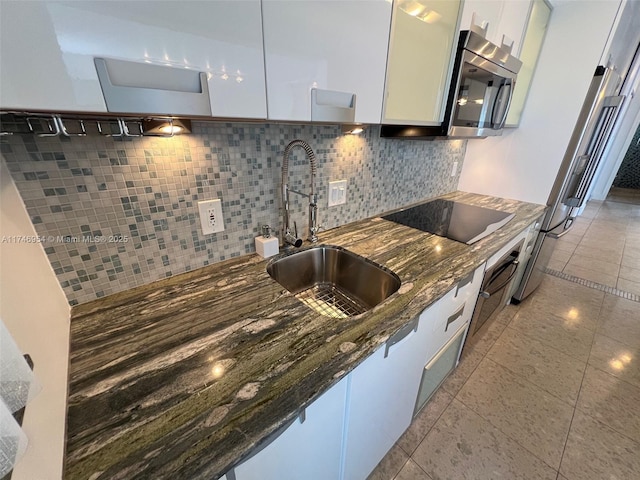 kitchen with black electric cooktop, a sink, white cabinets, dark stone counters, and stainless steel microwave