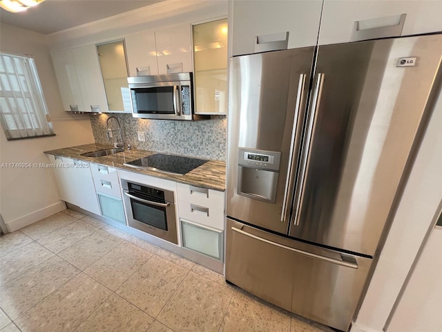 kitchen featuring appliances with stainless steel finishes, white cabinetry, a sink, and backsplash