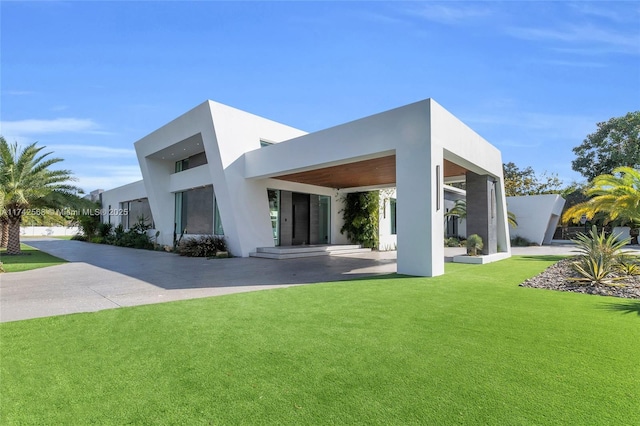 rear view of property featuring a lawn and stucco siding