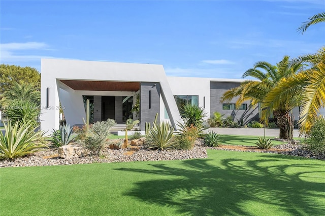 back of property with a yard and stucco siding