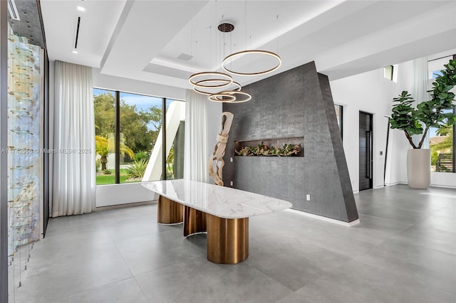 unfurnished dining area featuring a raised ceiling and finished concrete floors