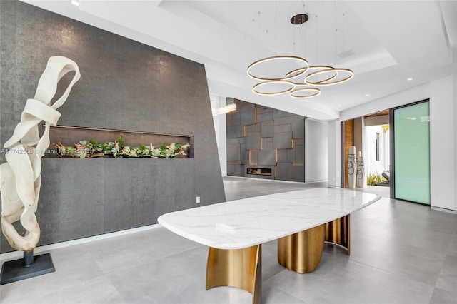 interior space with concrete flooring, recessed lighting, a raised ceiling, and an accent wall