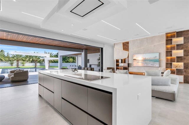 kitchen featuring a spacious island, modern cabinets, open floor plan, black electric stovetop, and light countertops