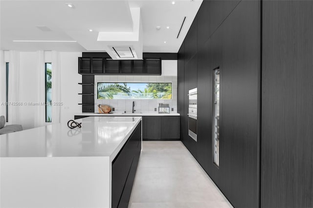 kitchen with light countertops, a large island, modern cabinets, and open shelves