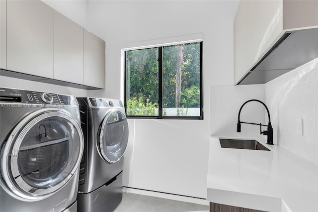 washroom featuring washing machine and dryer, a sink, and cabinet space