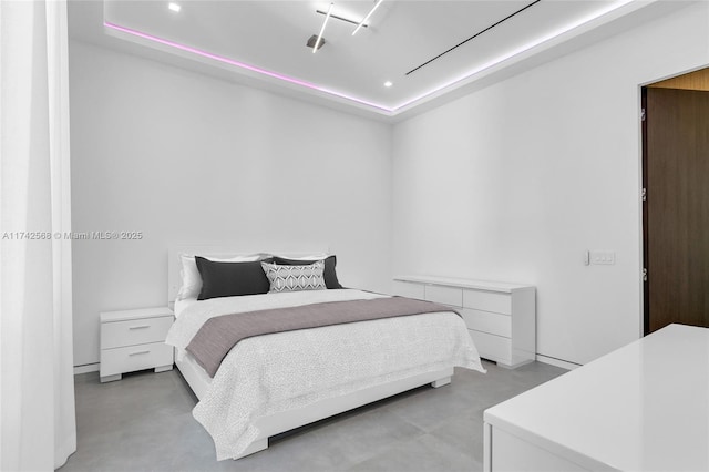 bedroom with finished concrete floors, a raised ceiling, and recessed lighting