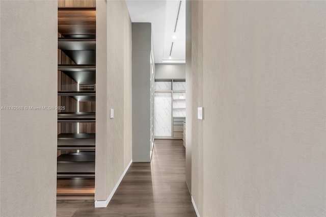 hallway featuring baseboards, dark wood-style flooring, and a textured wall