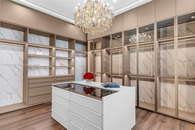 walk in closet featuring an inviting chandelier and wood finished floors