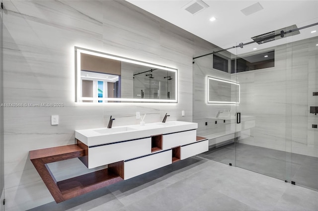 full bathroom featuring tile walls, double vanity, visible vents, a stall shower, and a sink