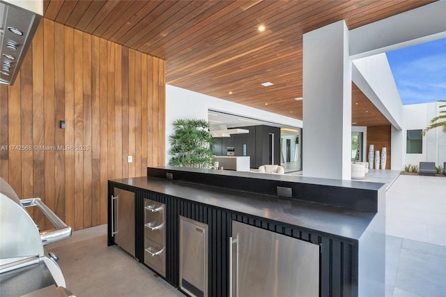 kitchen featuring refrigerator, dark countertops, wooden walls, dark cabinets, and wooden ceiling