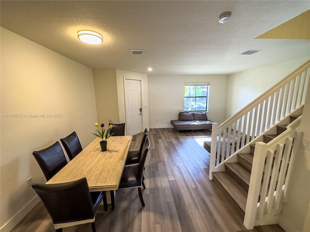 dining space with stairway, dark wood-style flooring, visible vents, and baseboards