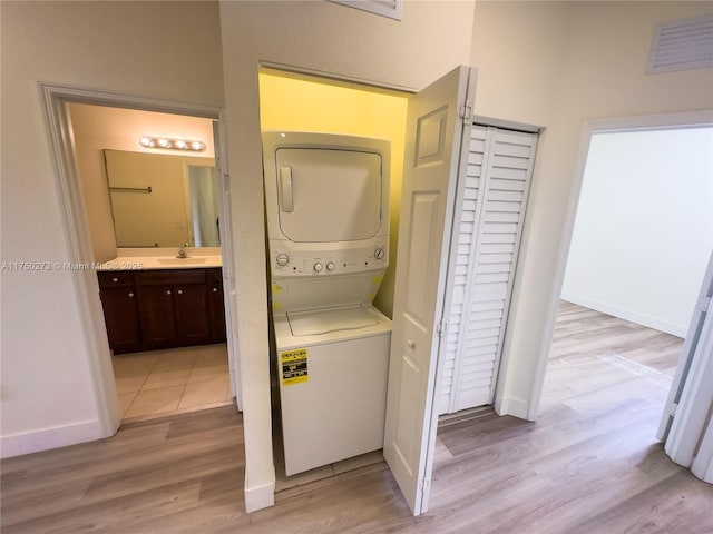 laundry room with laundry area, visible vents, light wood-style flooring, stacked washing maching and dryer, and a sink