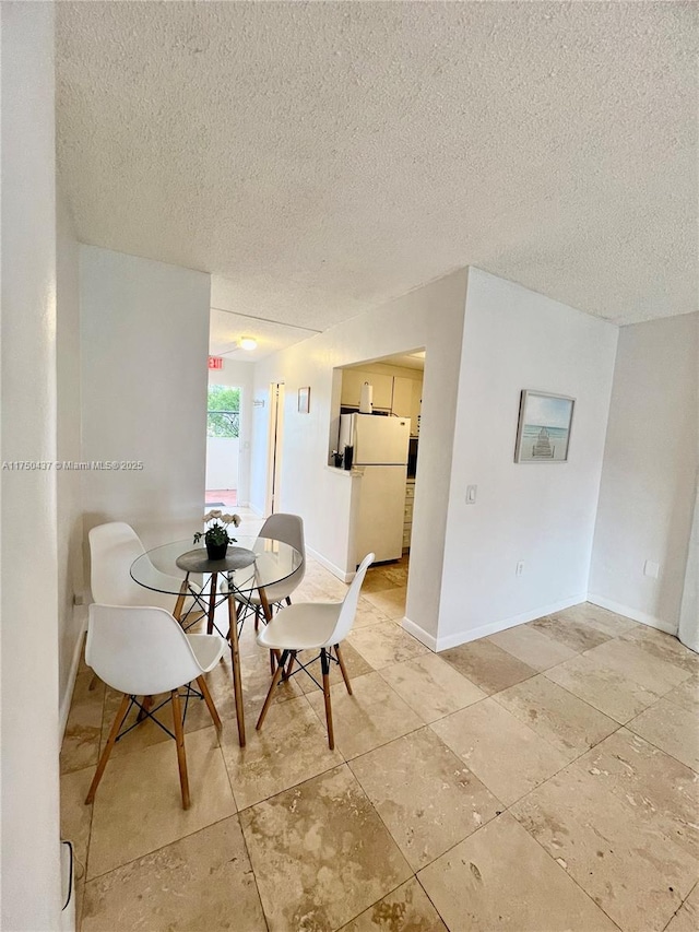 dining area with a textured ceiling and baseboards