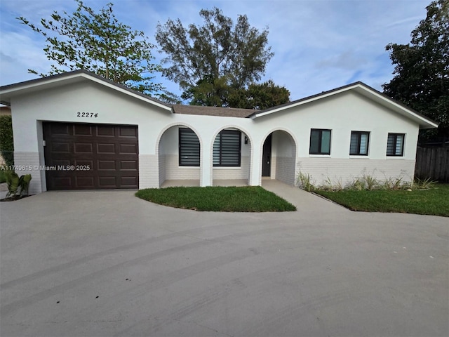 ranch-style house with brick siding, driveway, an attached garage, and stucco siding