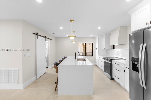 22274 SW 61st Ave, Boca Raton, FL 33428 - kitchen featuring appliances with stainless steel finishes, a barn door, premium range hood, a kitchen island with sink, and white cabinetry
