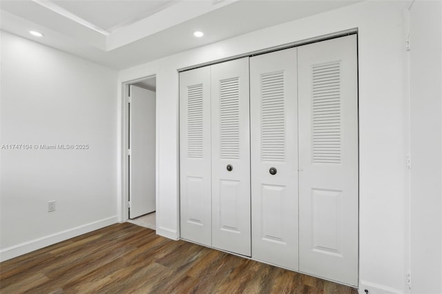 unfurnished bedroom with baseboards, dark wood finished floors, a closet, and recessed lighting