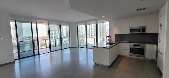 kitchen with visible vents, expansive windows, white cabinetry, stainless steel appliances, and a peninsula