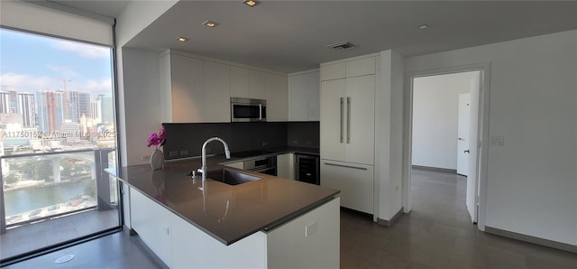 kitchen with paneled refrigerator, visible vents, a sink, stainless steel microwave, and a peninsula