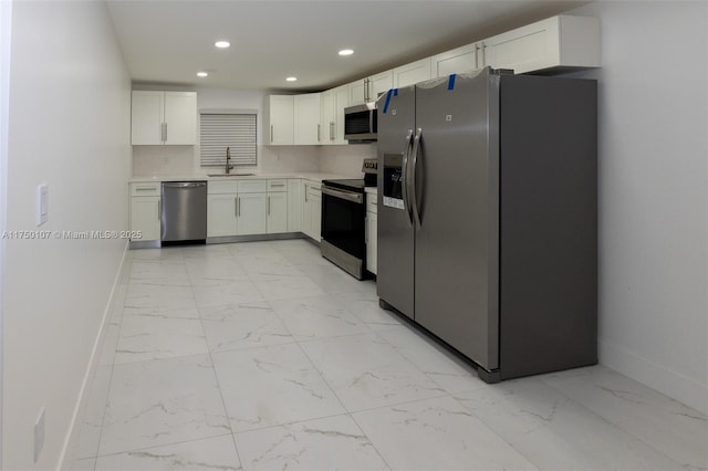 kitchen with marble finish floor, stainless steel appliances, white cabinetry, a sink, and recessed lighting