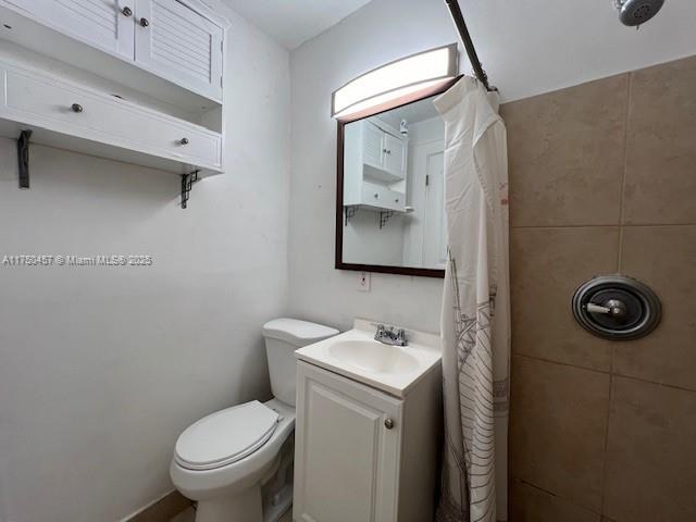 full bathroom featuring tiled shower, vanity, and toilet