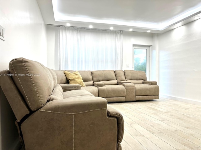 living area featuring light wood-style flooring, a tray ceiling, baseboards, and recessed lighting