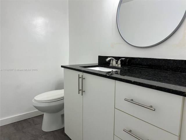 bathroom featuring baseboards, vanity, and toilet