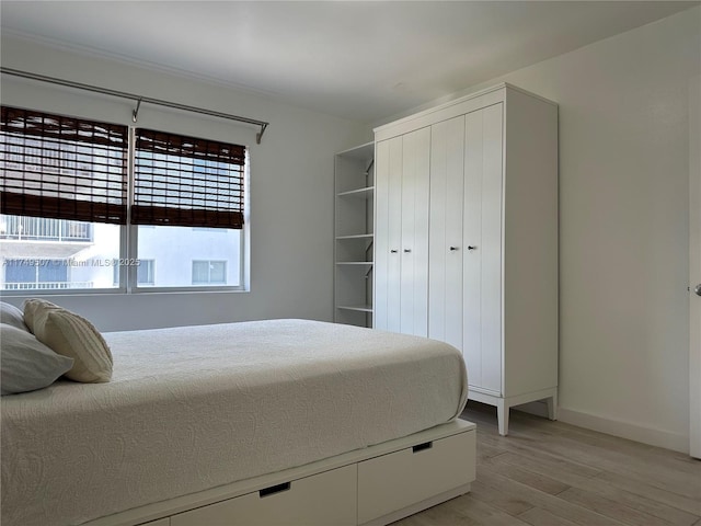 bedroom with light wood finished floors and baseboards