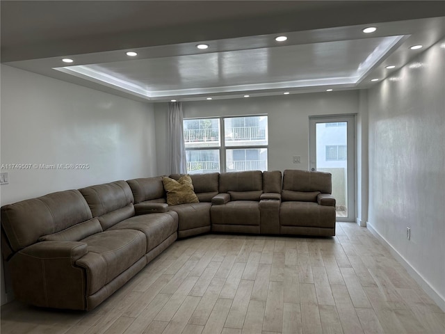 living area featuring light wood finished floors, a tray ceiling, baseboards, and recessed lighting