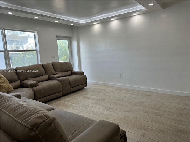 living area with recessed lighting, a tray ceiling, light wood-style flooring, and baseboards