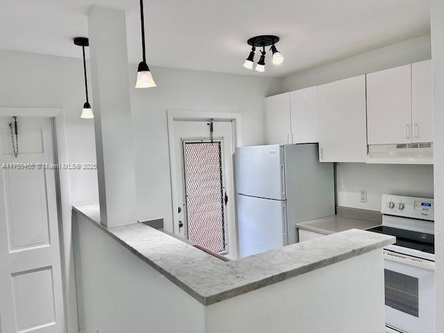 kitchen with decorative light fixtures, light countertops, white cabinets, white appliances, and under cabinet range hood