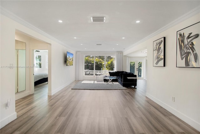 unfurnished living room featuring light wood-type flooring, visible vents, and crown molding