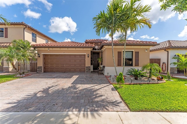 mediterranean / spanish home with an attached garage, a front yard, decorative driveway, and stucco siding