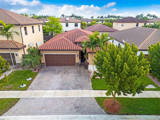 mediterranean / spanish-style home with a garage, a residential view, a tiled roof, decorative driveway, and stucco siding