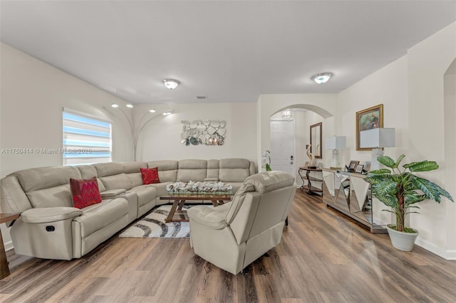 living area with arched walkways, wood finished floors, and visible vents
