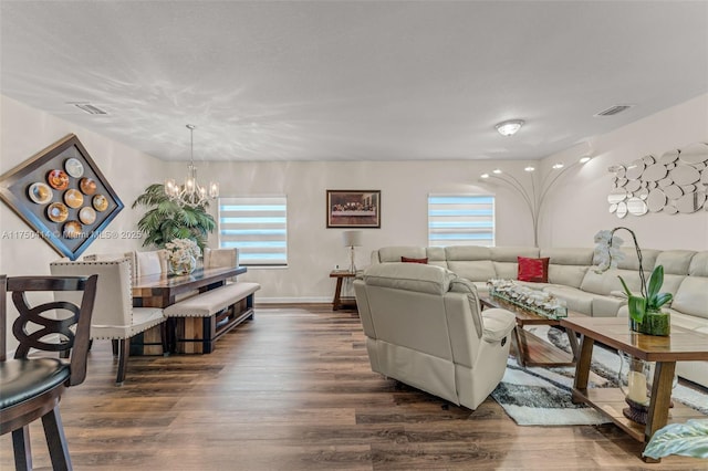 living area with a chandelier, dark wood-type flooring, visible vents, and baseboards