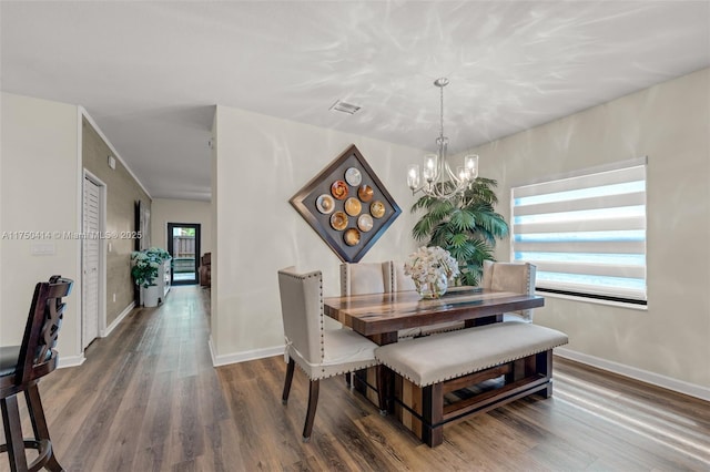 dining room featuring dark wood-type flooring, visible vents, a notable chandelier, and baseboards